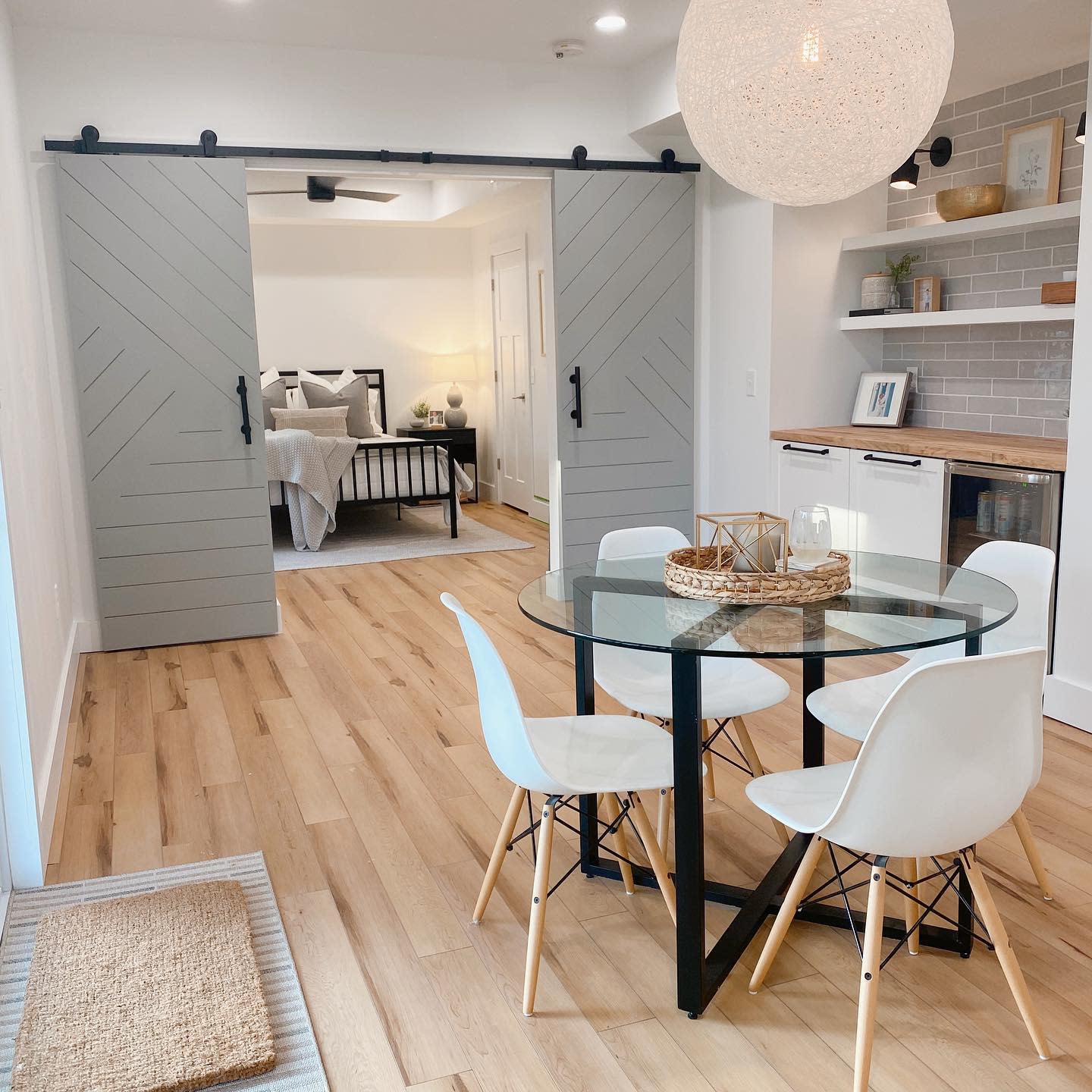 open plan apartment round glass table white chairs barn door to bedroom bar fridge 